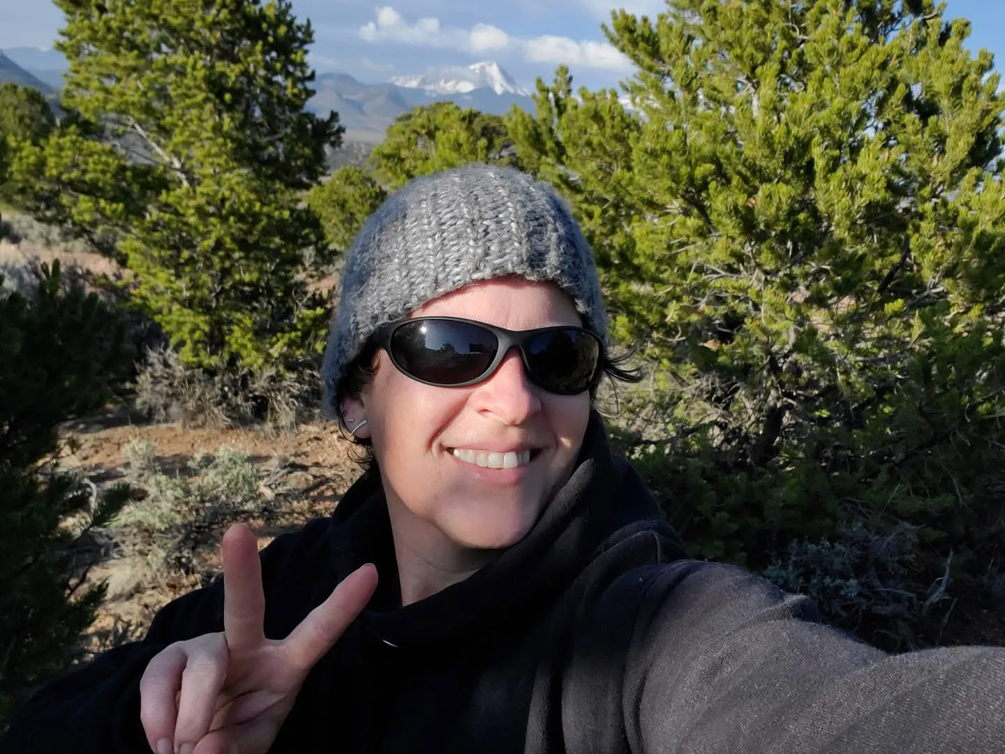 Cheryl outdoors with snow-capped mountains behind her